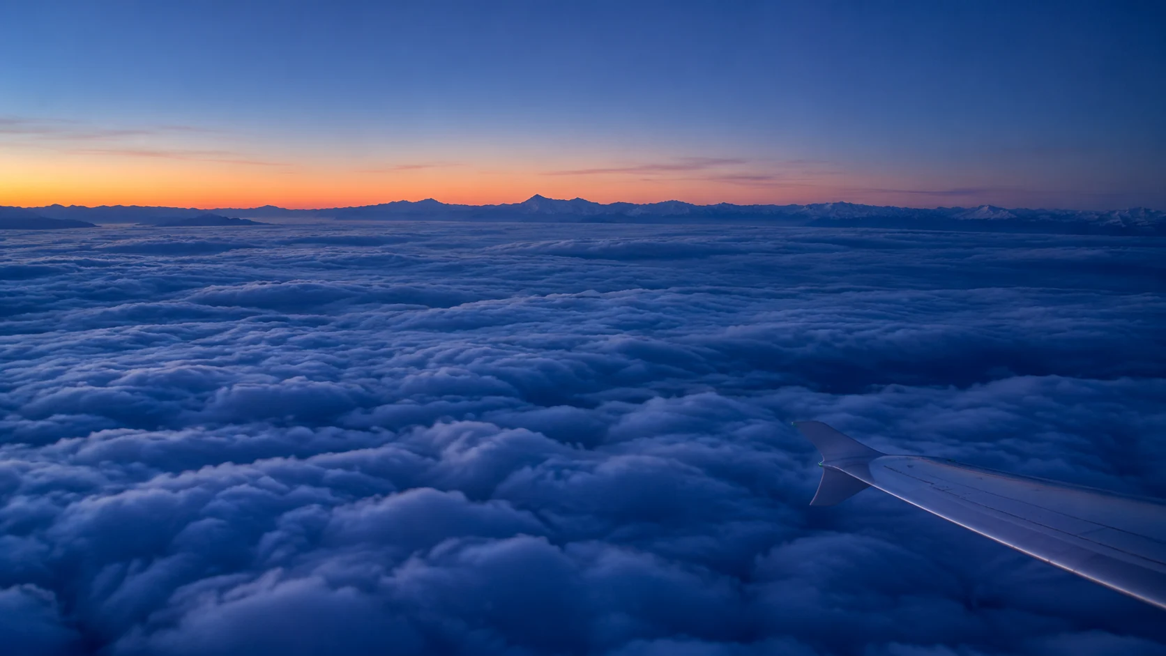 Soft evening light over clouds and mountains, seen from an aircraft